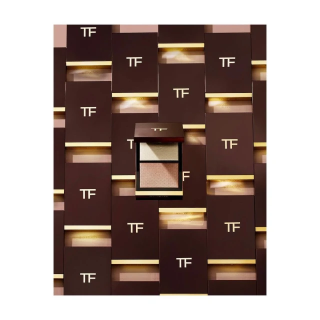 Tom Ford eyeshadow palette with multiple color pans, displayed against a background of TF-branded boxes and gold accents.