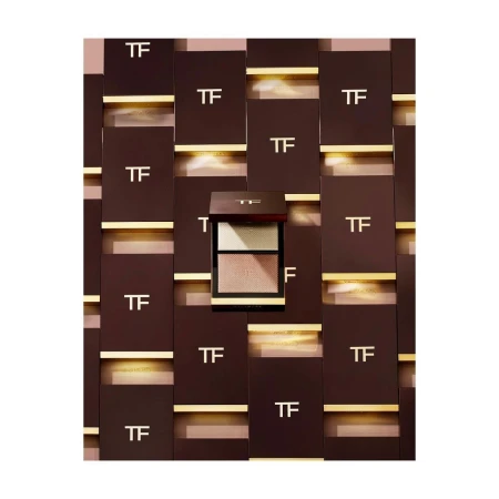 Tom Ford eyeshadow palette with multiple color pans, displayed against a background of TF-branded boxes and gold accents.