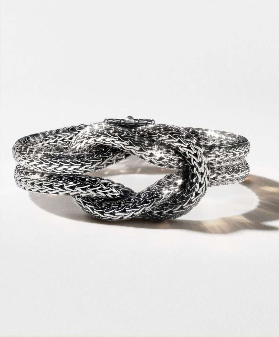 Silver braided knot bracelet on a white background. Jewelry design close-up highlights the texture and form of the luxury accessory.