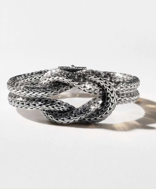 Silver braided knot bracelet on a white background. Jewelry design close-up highlights the texture and form of the luxury accessory.