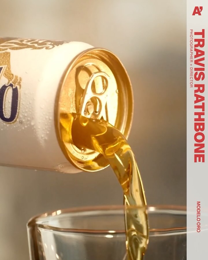 Close-up of Modelo Oro beer pouring from a white and gold can into a glass, highlighting the beverage's golden hue and refreshing texture.