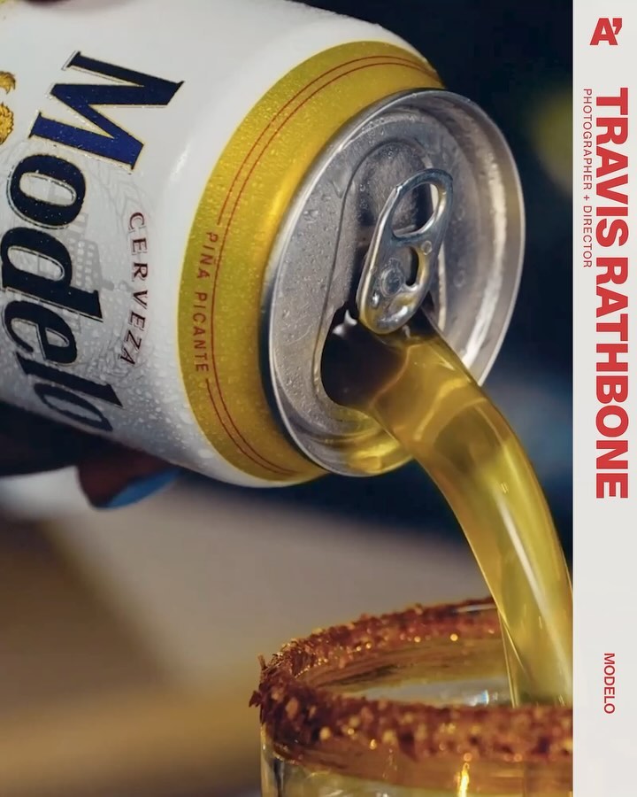 Close-up of a Modelo beer can pouring beer into a glass with a chili-salt rim; a refreshing and spicy beverage.