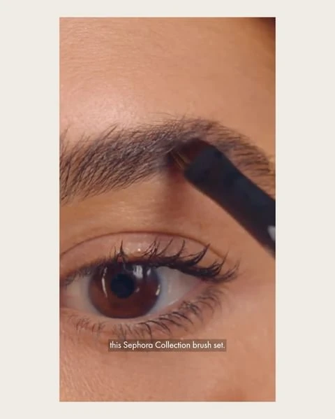 Close-up of a woman applying eyebrow makeup with a brush. Focus on the eye, eyebrow, and cosmetic brush for beauty and makeup.