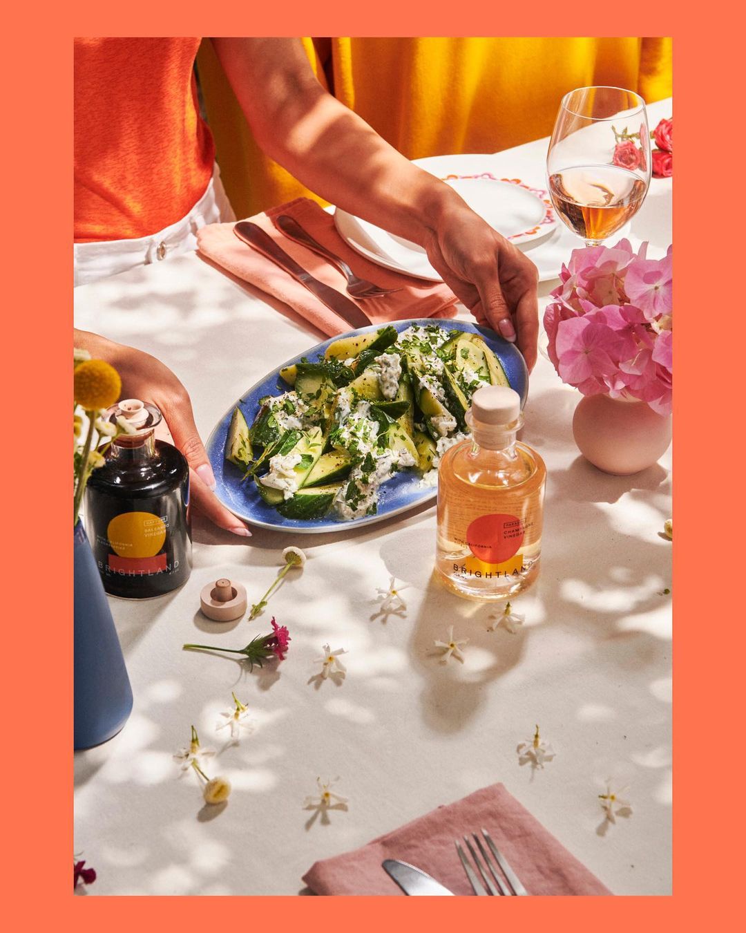 Overhead shot of a table set with fresh zucchini salad, drinks, flowers, and table setting for a light and airy meal.