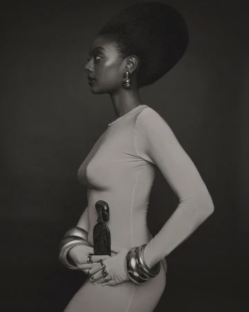 Profile portrait of an African American woman with an afro in a light dress, wearing several bangles and holding a dark statue.