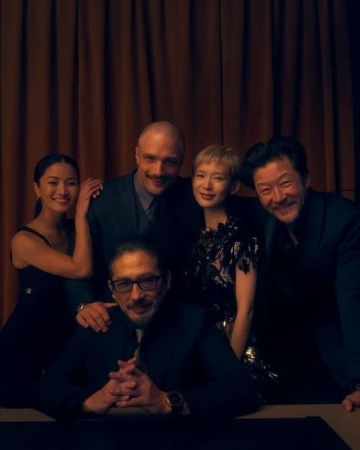 Group portrait of five adults posing together indoors against a dark curtain background by photographer Kendall Bessent.