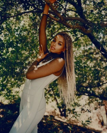 Black woman with long blonde box braids posing amidst tree branches in Los Angeles, photographed by Kendall Bessent