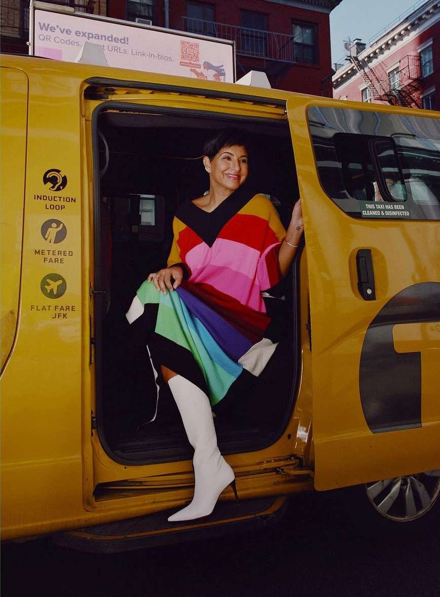 Stylish woman in colorful dress exits a yellow taxi in urban setting, showcasing fashion and city life.