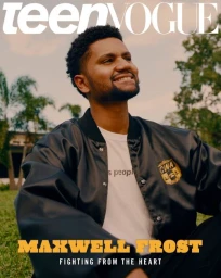Portrait of a smiling young Black man wearing a black satin bomber jacket seated outdoors on grass