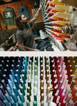 Man with tattoos reaching for colorful spools of thread on a rack. Display of thread with spools of colorful thread in a workshop setting.