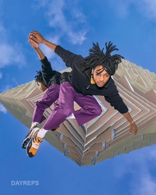Upside-down view of a young adult male posing near modern architecture against a blue sky, creating a dynamic and surreal urban scene.