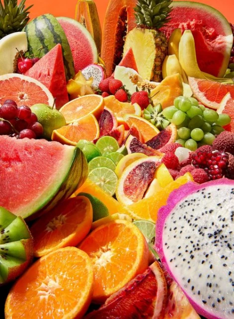 Overhead shot of vibrant and colorful mix of fresh fruits including watermelon, oranges, kiwi, pineapple, papaya, and dragon fruit.