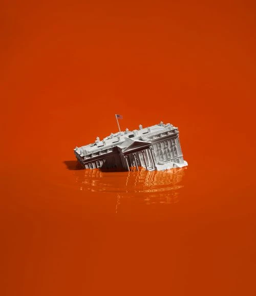 White House miniature submerged in orange liquid with reflections, creating a surreal and visually striking image.