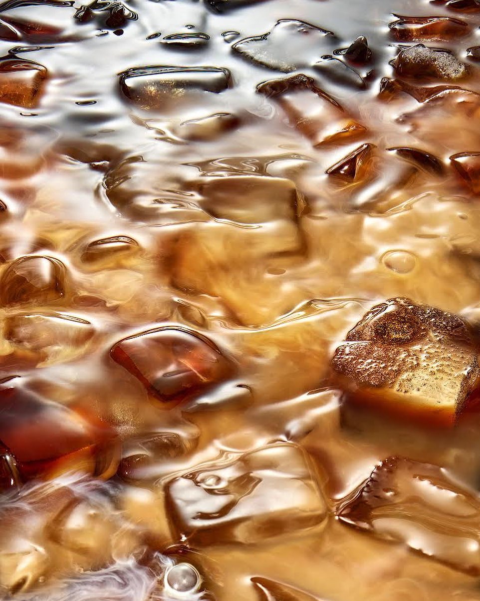 Iced coffee with coffee cubes and cream swirling together, creating a refreshing and visually appealing beverage.