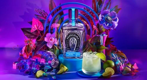 Herradura tequila bottle and cocktail on a blue platform, framed by exotic flowers and neon blue arches against a purple backdrop.