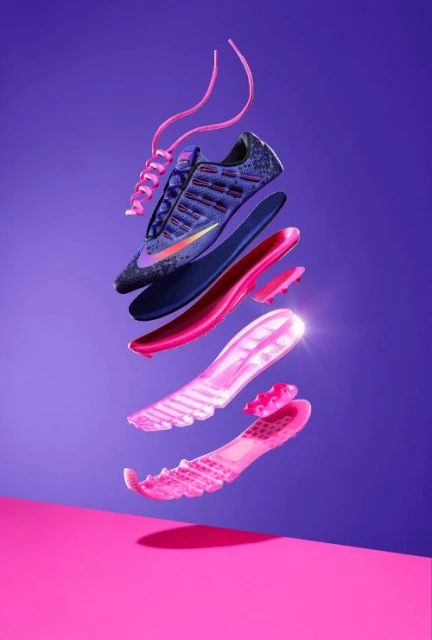 Deconstructed running shoe with layers floating on a split purple and pink background, showcasing design and construction.
