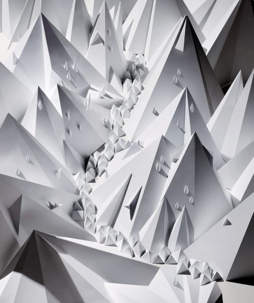 Abstract paper art featuring an array of geometric, triangular shapes and forms in shades of white, creating a visually stunning pattern.