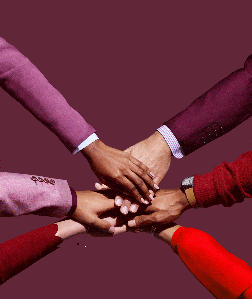 Diverse hands clasped together in a gesture of unity and teamwork against a solid plum background, highlighting coordination.