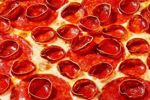 Overhead close-up of a pepperoni pizza with melted cheese and red pepperoni slices covering the surface.
