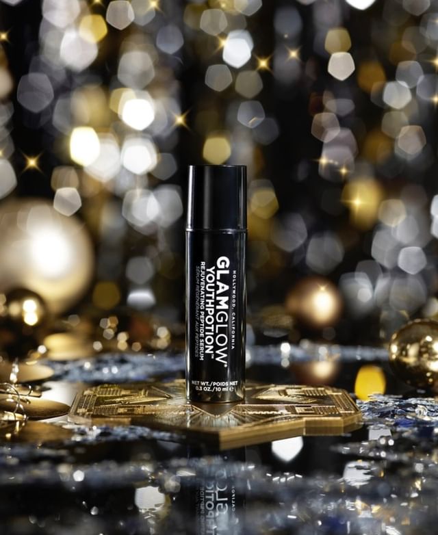 GlamGlow Youthpotion serum on gold surface with bokeh lights in the background for beauty, fashion, and cosmetic advertising.