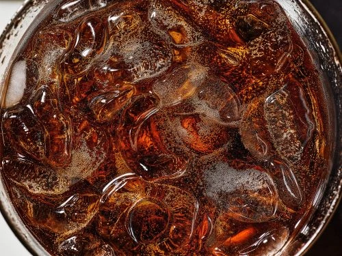 Close-up of a glass filled with a dark beverage and ice cubes, creating a refreshing and visually appealing image of a cold drink.