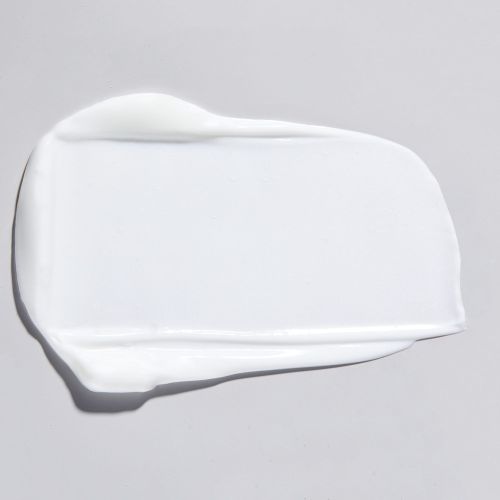 Close-up studio shot of a smear of white cream on a light gray background, emphasizing texture and skincare product quality.