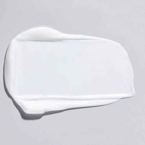 Close-up studio shot of a smear of white cream on a light gray background, emphasizing texture and skincare product quality.