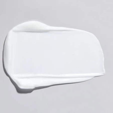 Close-up studio shot of a smear of white cream on a light gray background, emphasizing texture and skincare product quality.