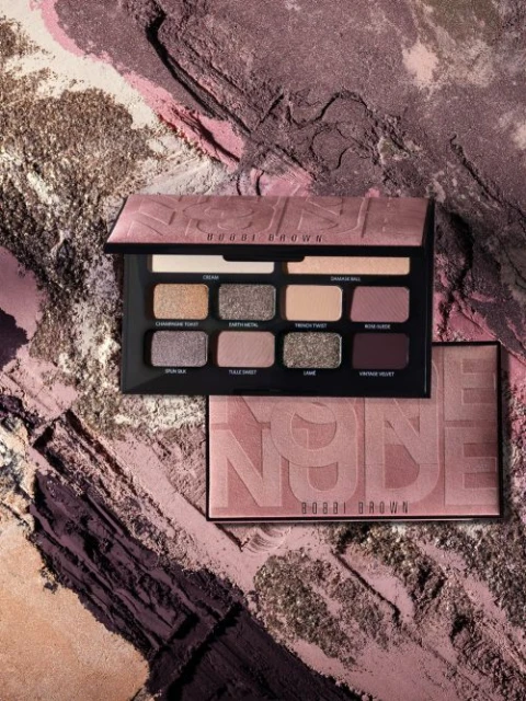 Bobbi Brown Nude Eyeshadow Palette on a textured cosmetic powder background, close-up studio shot for makeup beauty advertising.