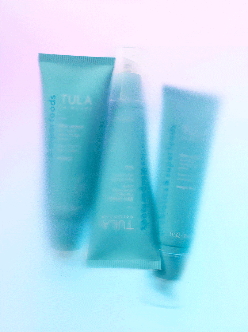 Three turquoise tubes of Tula skincare products are arranged against a gradient background ranging from lavender to baby blue.