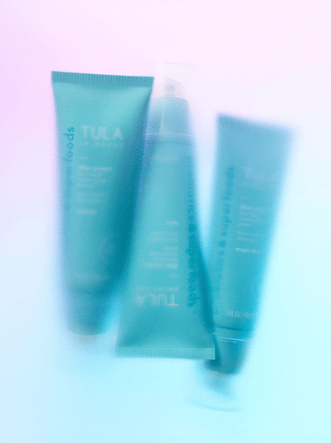 Three turquoise tubes of Tula skincare products are arranged against a gradient background ranging from lavender to baby blue.