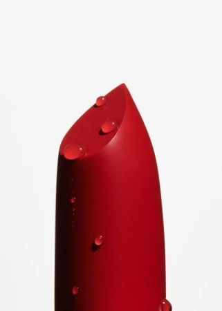 Close-up shot of a red lipstick with water droplets on a white background for beauty product photography and cosmetics advertising.