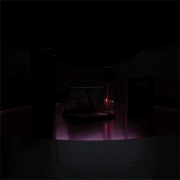 Dark product shot of an open laptop and glass against a black background with purple-pink light emitting below the objects.