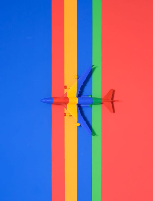 Overhead shot of toy airplane on colorful stripes: blue, yellow, green, and red. Vibrant, eye-catching abstract pattern.