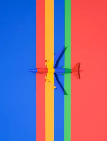Overhead shot of toy airplane on colorful stripes: blue, yellow, green, and red. Vibrant, eye-catching abstract pattern.
