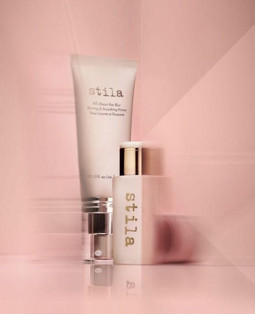 Two Stila beauty product bottles displayed on a pink surface, with studio lighting and blurred motion in the background, cosmetics.
