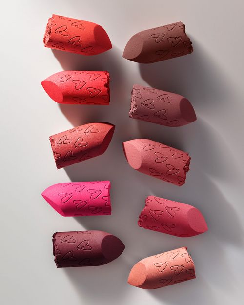Assortment of colorful makeup blender sponges with heart patterns arranged on a white surface, showcasing beauty accessories.