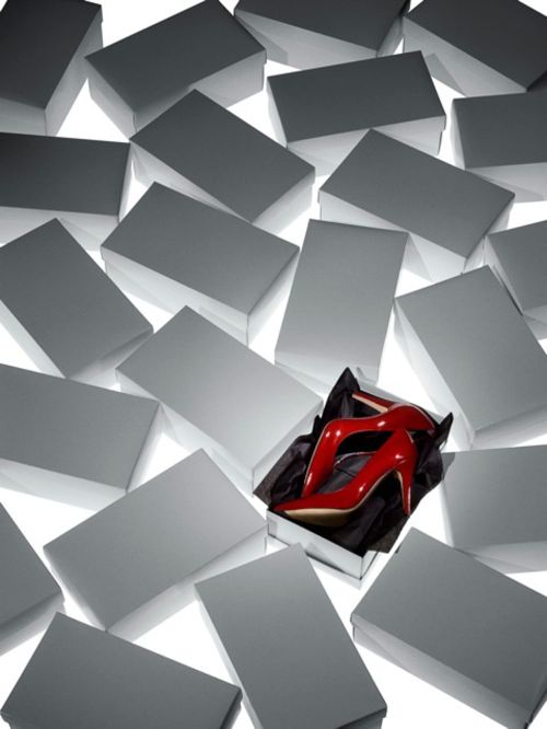 Striking shot of red high heels in a gift box surrounded by numerous closed white boxes, creating a visually compelling retail image.