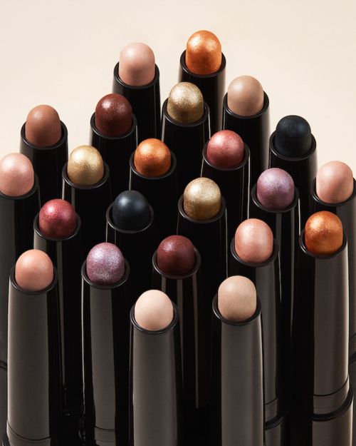 Arrangement of black cosmetic sticks with colorful tops, displayed in a studio setting, perfect for showcasing beauty products.