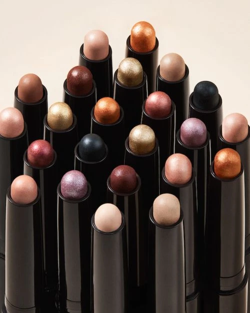 Arrangement of black cosmetic sticks with colorful tops, displayed in a studio setting, perfect for showcasing beauty products.