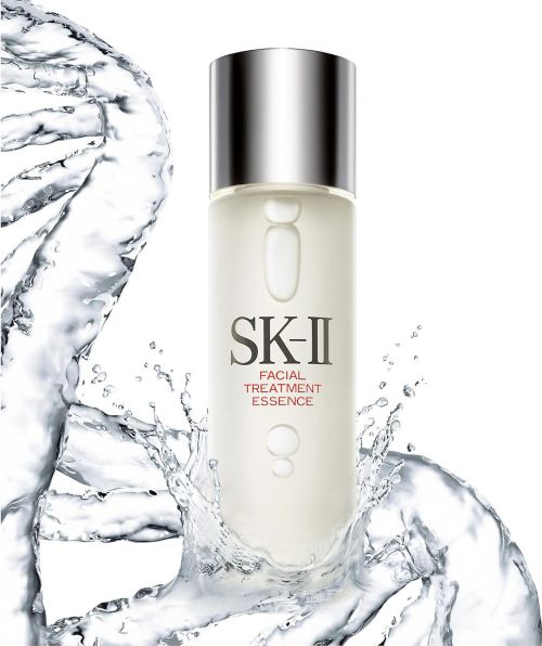 SK-II Facial Treatment Essence bottle in studio shot with water splash elements, silver cap, clear bottle on white background.