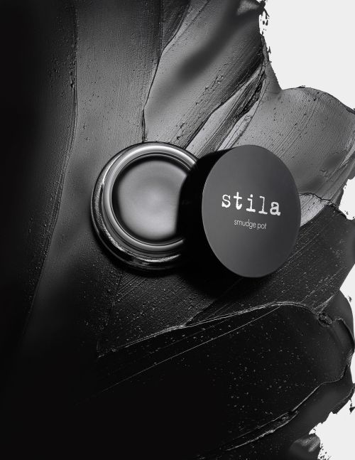 Stila smudge pot cream eyeshadow on a black smeared background. Beauty still life with cosmetic product, studio shot.