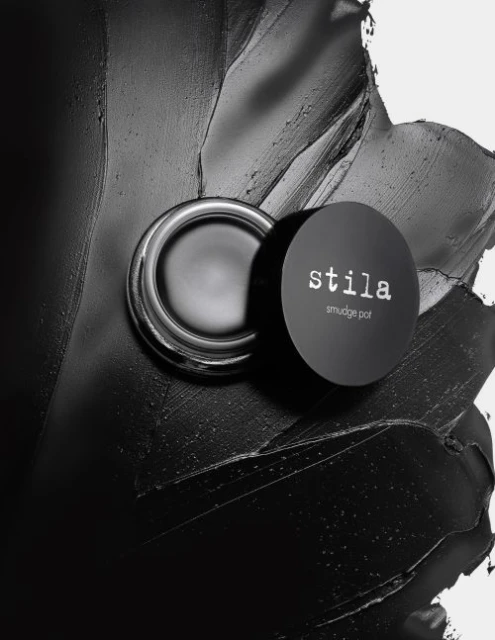 Stila smudge pot cream eyeshadow on a black smeared background. Beauty still life with cosmetic product, studio shot.