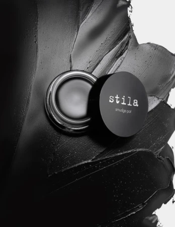 Stila smudge pot cream eyeshadow on a black smeared background. Beauty still life with cosmetic product, studio shot.