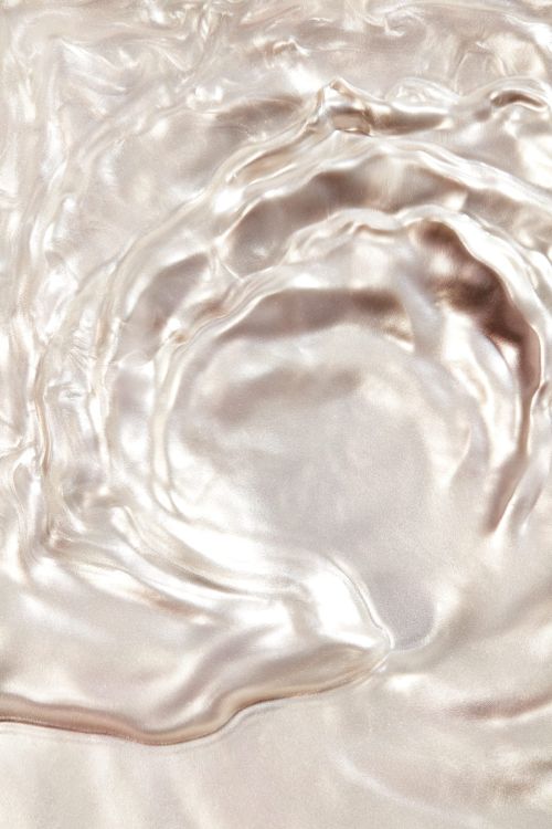 Close-up abstract texture featuring rippled waves of shimmering, reflective white and silver material, creating a fluid, pearlescent background.