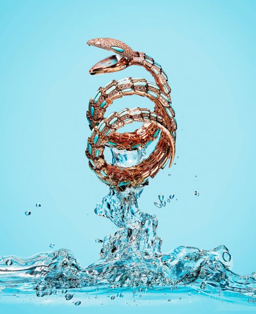 Spiral snake bracelet jewelry in water on a light blue background in a studio shot for fashion and beauty advertising visuals.