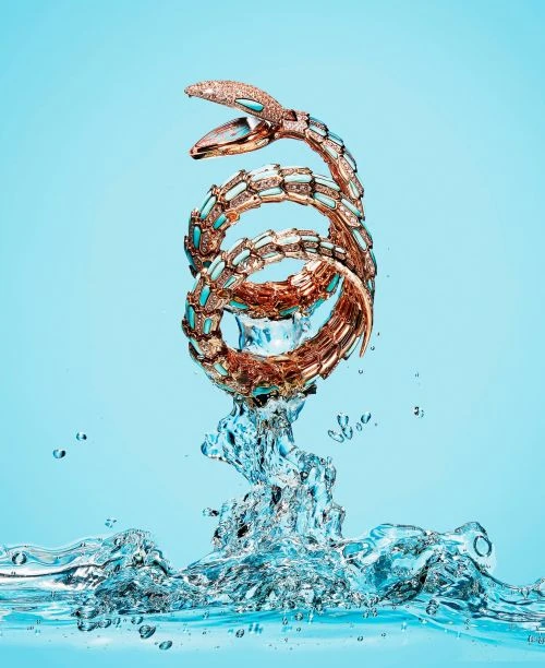 Spiral snake bracelet jewelry in water on a light blue background in a studio shot for fashion and beauty advertising visuals.