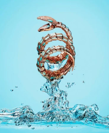 Spiral snake bracelet jewelry in water on a light blue background in a studio shot for fashion and beauty advertising visuals.