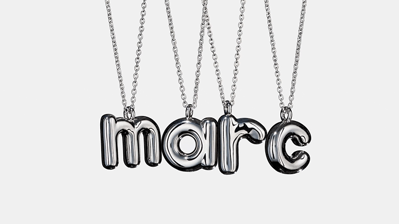 Shiny silver 'marc' letter pendants hang from delicate silver chains against an off-white backdrop in a clean studio product shot.
