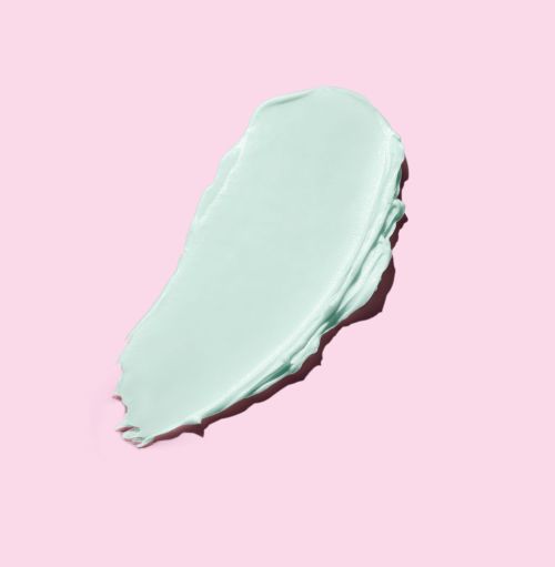 Macro studio shot of a turquoise-colored cosmetic cream swatch against a light pink background; ideal for beauty and skincare product promotion.